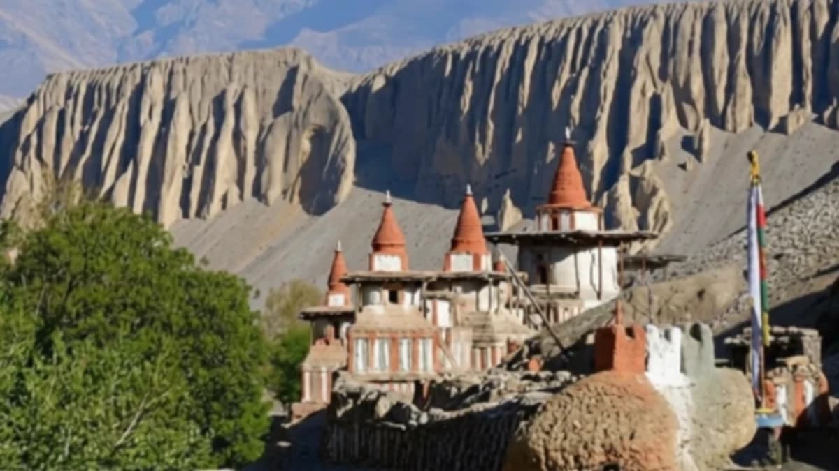 Ancient Buddhist stupas in front of large desert cliffs in Upper Mustang, Nepal.