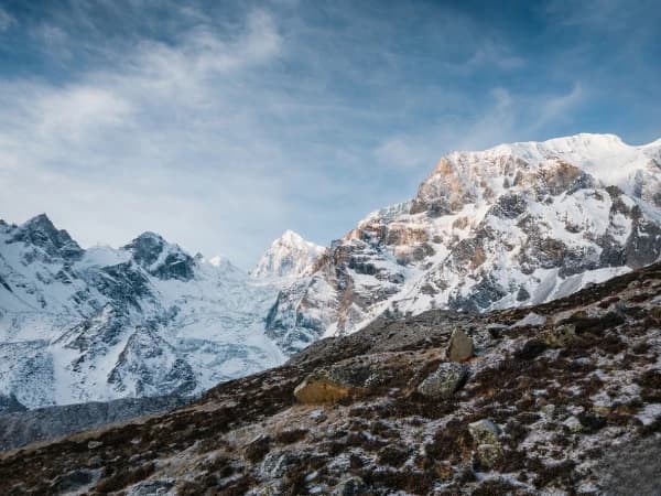 Traditional Buddhist chortens in the Manaslu Circuit Trek region with eroded cliffs and Himalayan mountains.
